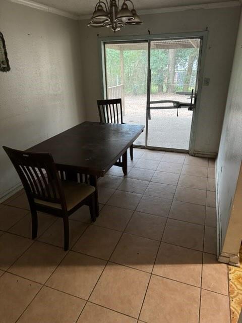 dining room featuring an inviting chandelier, a healthy amount of sunlight, crown molding, and light tile patterned flooring