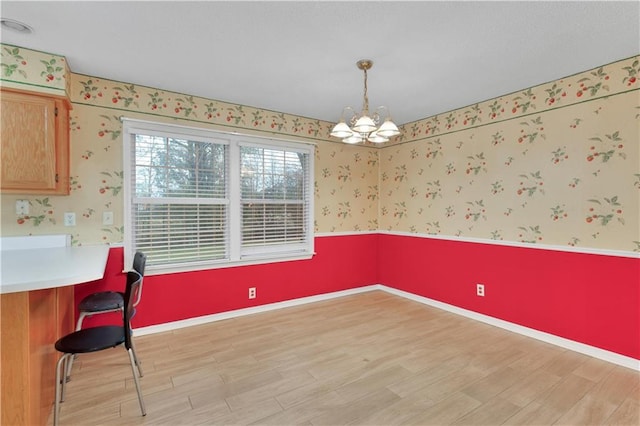 dining space with light hardwood / wood-style floors and a notable chandelier