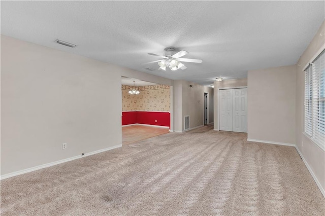 carpeted spare room with ceiling fan with notable chandelier