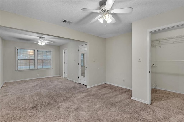 unfurnished bedroom with ceiling fan, a closet, light carpet, and a textured ceiling