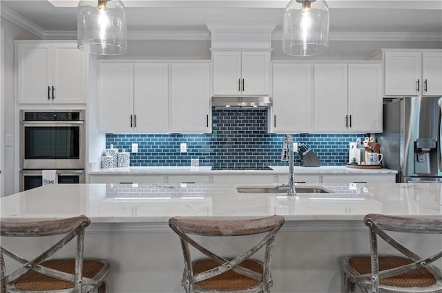 kitchen with appliances with stainless steel finishes, pendant lighting, a breakfast bar area, and white cabinets