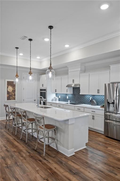 kitchen with pendant lighting, white cabinets, appliances with stainless steel finishes, and a large island with sink