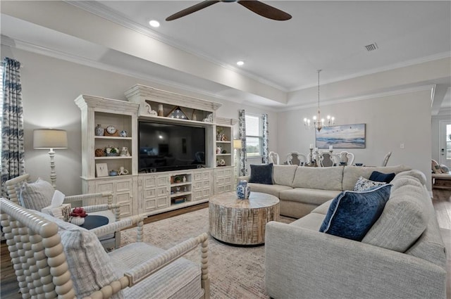 living room with crown molding, wood-type flooring, a tray ceiling, and ceiling fan with notable chandelier