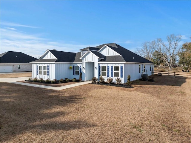 view of front of house with central AC and a front lawn