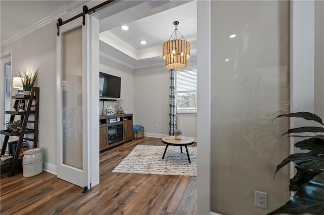 living room featuring dark hardwood / wood-style flooring, crown molding, a barn door, and a raised ceiling