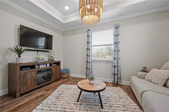 living room featuring a tray ceiling, hardwood / wood-style flooring, ornamental molding, and an inviting chandelier