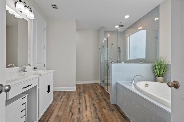 bathroom featuring hardwood / wood-style flooring, vanity, and plus walk in shower