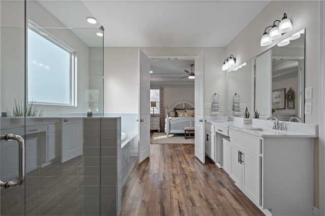 bathroom with hardwood / wood-style flooring, ceiling fan, vanity, and a bath