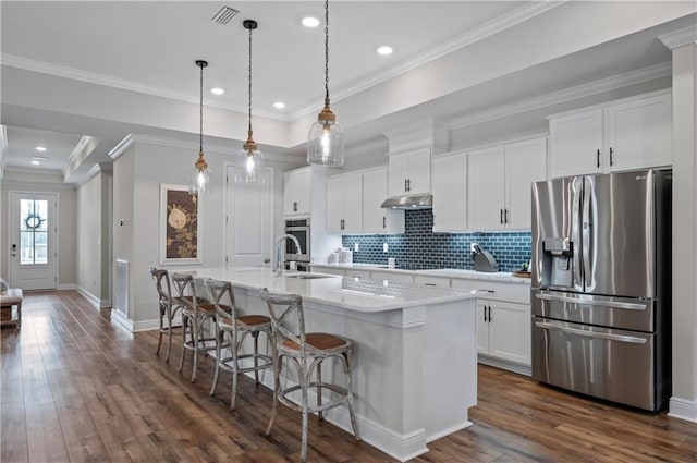 kitchen featuring pendant lighting, appliances with stainless steel finishes, white cabinetry, a kitchen breakfast bar, and an island with sink