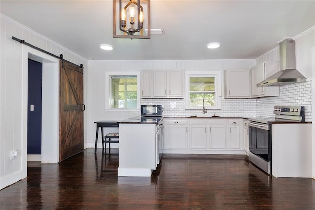 208 Beck St, Atmore, AL 36502 - kitchen featuring stainless steel electric stove, wall chimney range hood, black microwave, a barn door, and dark wood-style floors