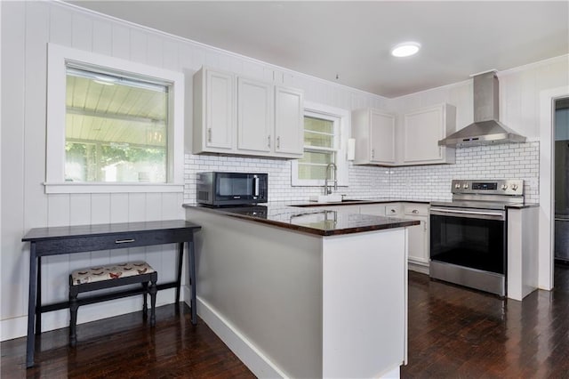 208 Beck St, Atmore, AL 36502 - kitchen featuring wall chimney exhaust hood, stainless steel range with electric stovetop, black microwave, dark wood-type flooring, and decorative backsplash