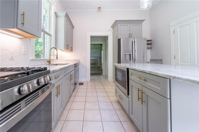 1703 Dauphin St, Mobile, AL 36604 - kitchen featuring appliances with stainless steel finishes, a sink, gray cabinets, light stone countertops, and backsplash