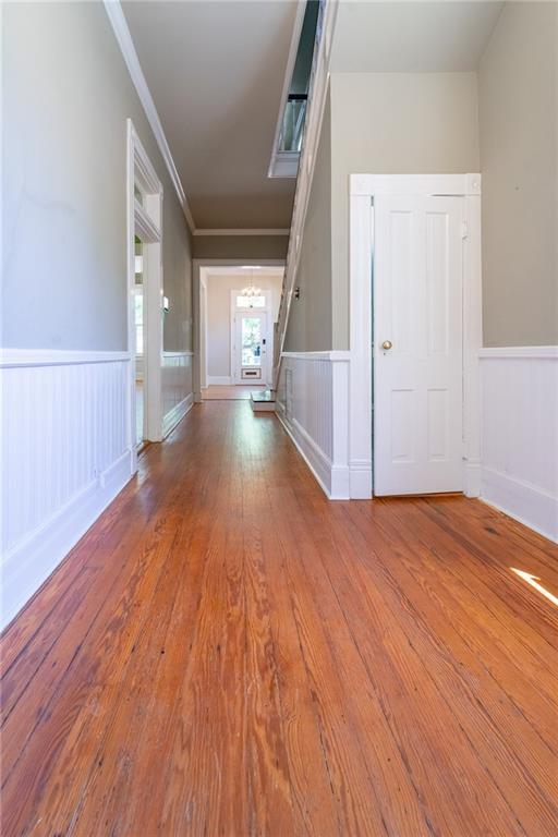 1703 Dauphin St, Mobile, AL 36604 - hallway featuring a chandelier, ornamental molding, a wainscoted wall, wood finished floors, and a decorative wall