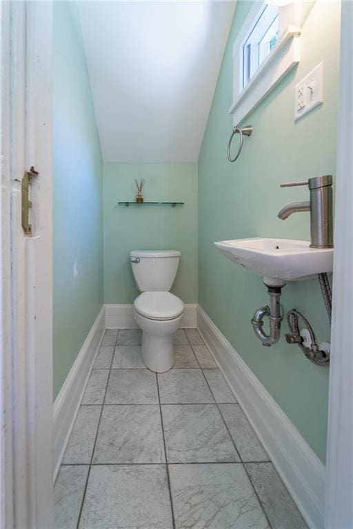 1703 Dauphin St, Mobile, AL 36604 - half bathroom featuring lofted ceiling, toilet, a sink, and baseboards