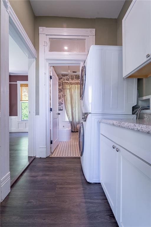 1703 Dauphin St, Mobile, AL 36604 - washroom with cabinet space, stacked washer / dryer, and dark wood-style flooring