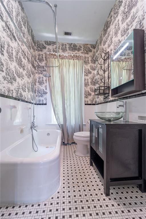 1703 Dauphin St, Mobile, AL 36604 - bathroom featuring wallpapered walls, toilet, vanity, and shower / tub combination
