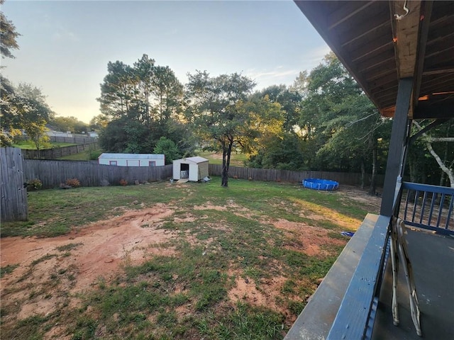 yard at dusk featuring a shed and a pool