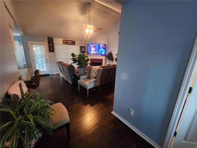 living room with dark wood-type flooring, ceiling fan, and vaulted ceiling