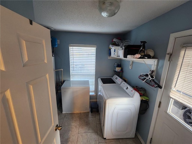 laundry area with light tile patterned floors, washing machine and clothes dryer, and a textured ceiling