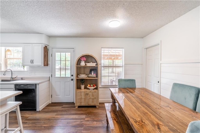 dining space featuring a textured ceiling, wainscoting, and dark wood-type flooring