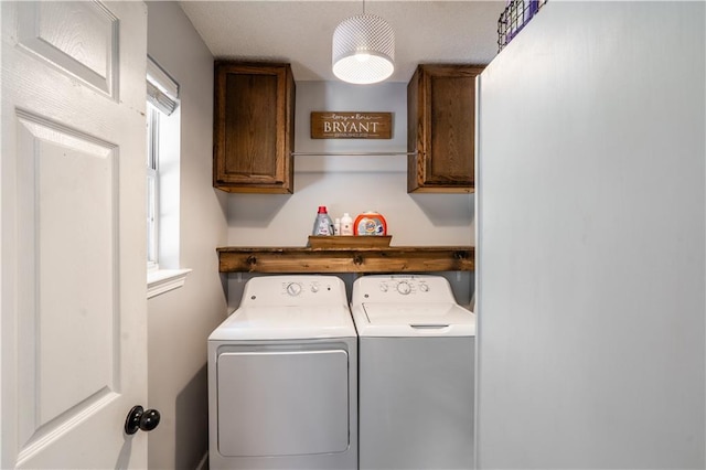 clothes washing area featuring cabinet space and washer and clothes dryer