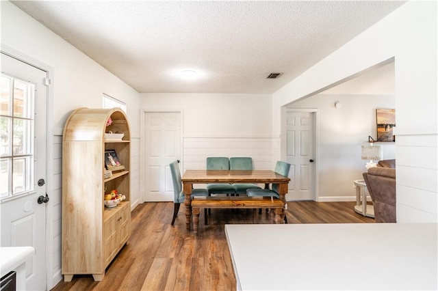 dining space with visible vents, a textured ceiling, and wood finished floors