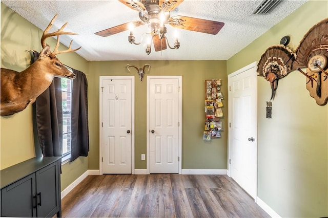 bedroom featuring a ceiling fan, dark wood-style flooring, a textured ceiling, visible vents, and baseboards