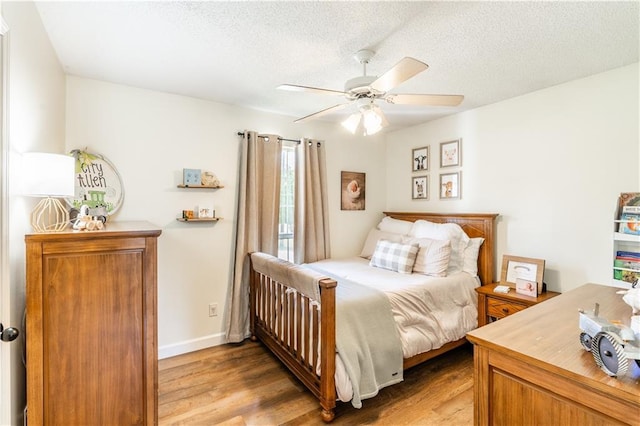 bedroom featuring baseboards, a ceiling fan, light wood finished floors, and a textured ceiling