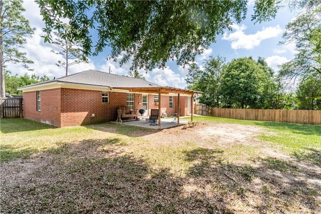 back of property with a lawn, brick siding, a fenced backyard, and a patio area