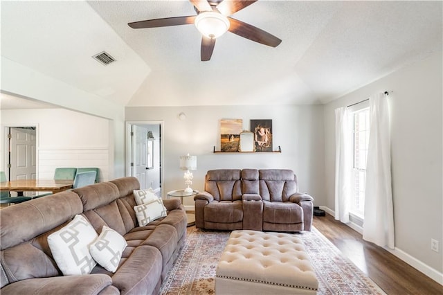 living room with a ceiling fan, baseboards, wood finished floors, lofted ceiling, and visible vents