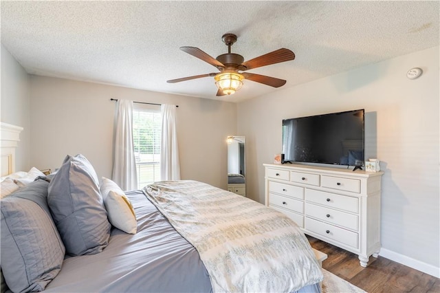 bedroom with a textured ceiling, baseboards, and dark wood-type flooring