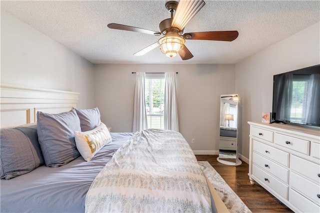 bedroom featuring baseboards, ceiling fan, dark wood finished floors, and a textured ceiling