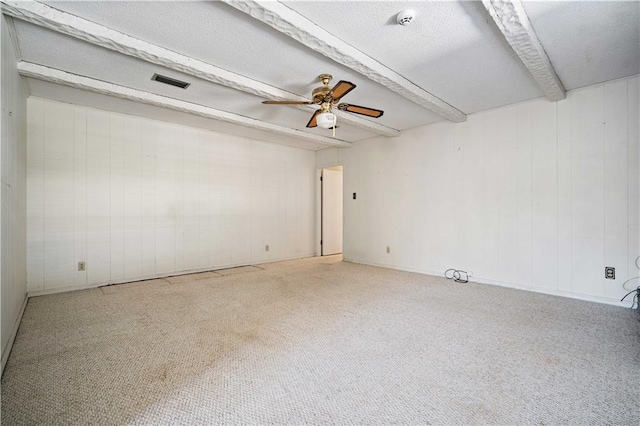 carpeted spare room featuring beamed ceiling and ceiling fan