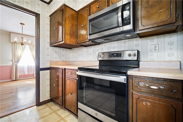 kitchen with light hardwood / wood-style flooring, stainless steel appliances, an inviting chandelier, and hanging light fixtures