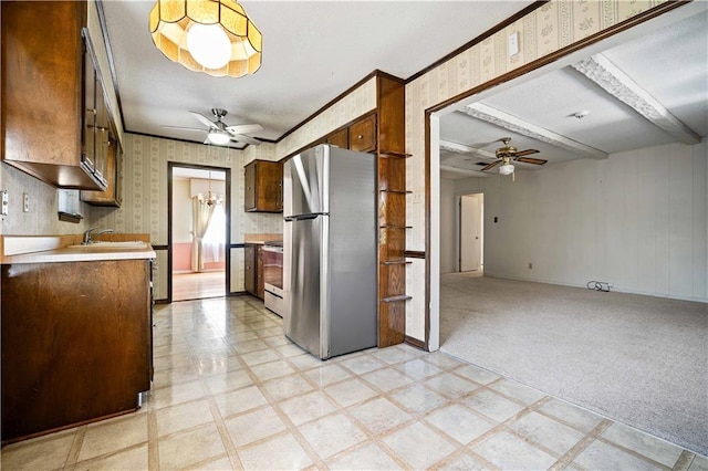 kitchen featuring beam ceiling, appliances with stainless steel finishes, sink, ceiling fan with notable chandelier, and light colored carpet