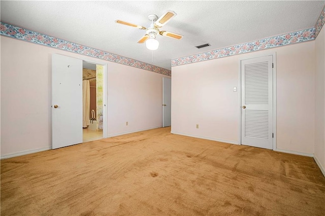 unfurnished bedroom with carpet, ensuite bathroom, a textured ceiling, and ceiling fan