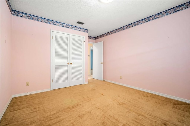 unfurnished bedroom with light carpet, a textured ceiling, and a closet