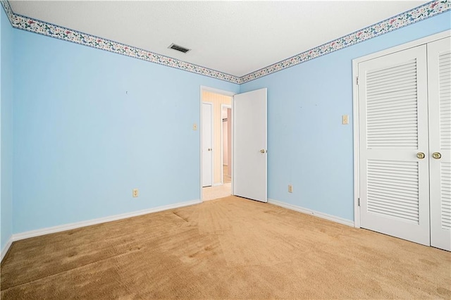 unfurnished bedroom featuring a closet and light colored carpet