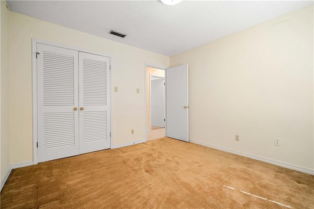 unfurnished bedroom featuring a closet and light carpet