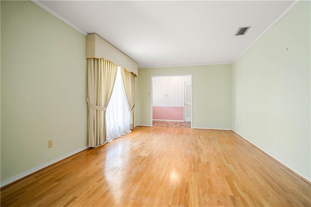 spare room with ornamental molding and light wood-type flooring