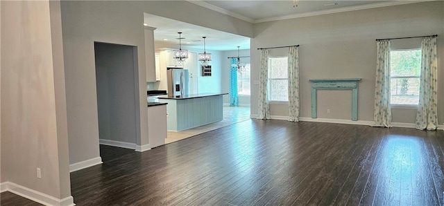 unfurnished living room with dark hardwood / wood-style flooring, ornamental molding, and a notable chandelier