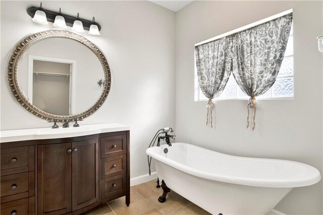 bathroom featuring a tub to relax in, vanity, and tile patterned flooring