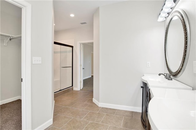 bathroom with an enclosed shower, vanity, and tile patterned flooring