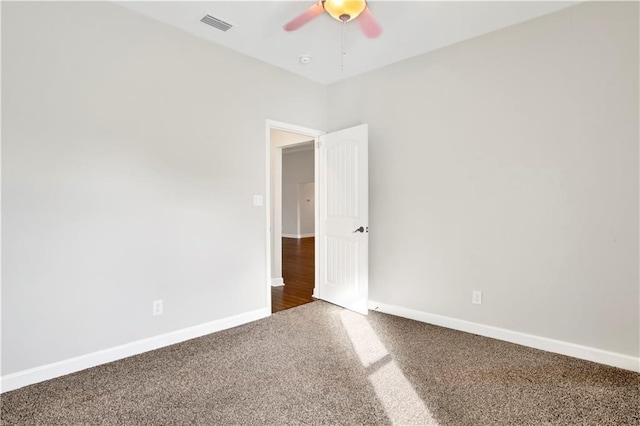 empty room featuring ceiling fan and dark carpet