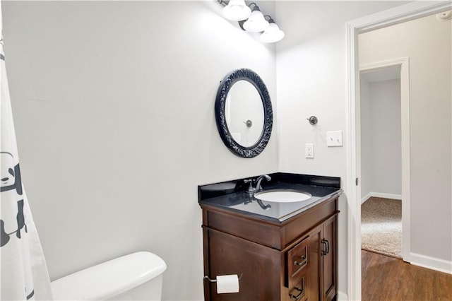 bathroom with toilet, vanity, and wood-type flooring