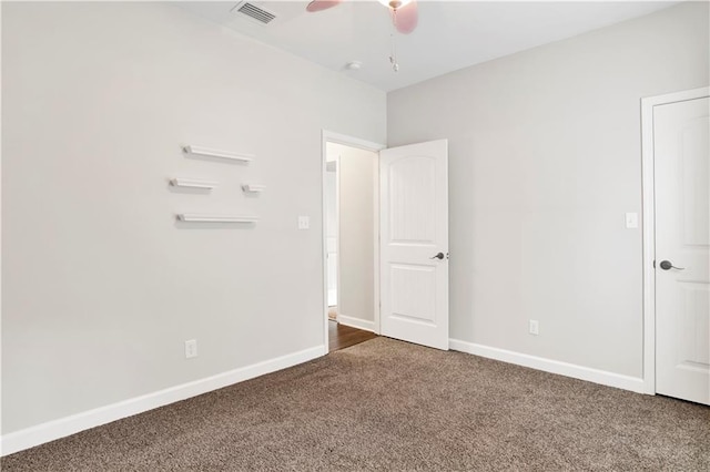 spare room with dark colored carpet and ceiling fan