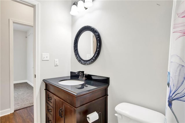 bathroom featuring toilet, wood-type flooring, and vanity