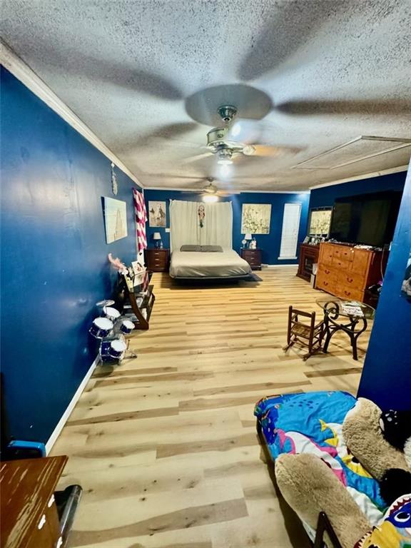 bedroom with hardwood / wood-style flooring, ceiling fan, ornamental molding, and a textured ceiling