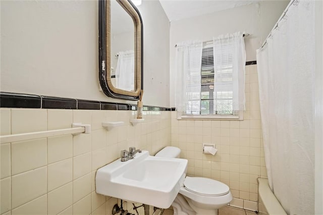 full bath with a wainscoted wall, a sink, toilet, and tile walls