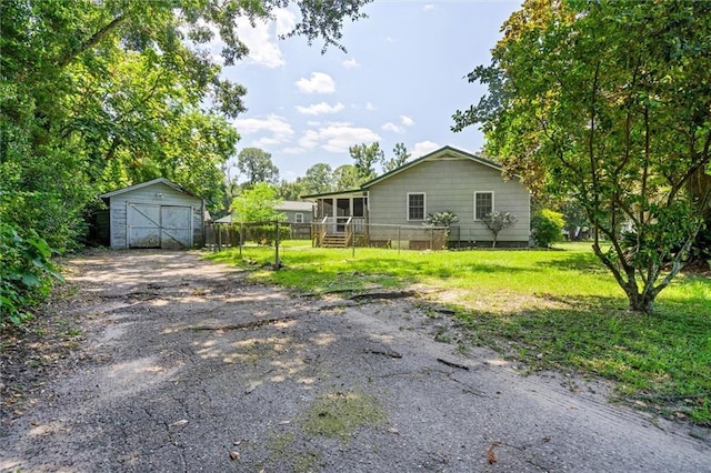 view of front of property featuring a garage, an outbuilding, fence, and a front lawn